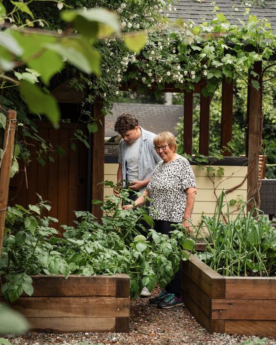 Großmutter und Enkel arbeiten im Gemüsegarten hinter dem Haus