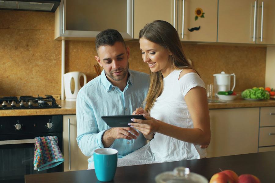 Paar in der Küche schaut gemeinsam auf ein Tablet
