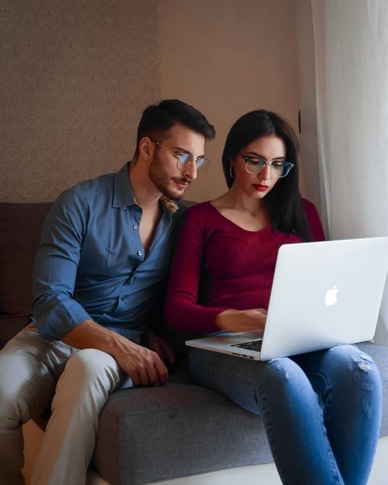 Paar auf dem Sofa vergleicht Angebote am Laptop